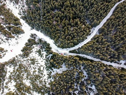 Aerial view of of the official and emergency vehicles and some spectators at a check point of a winter rally near Comandau, Covasna, Romania photo