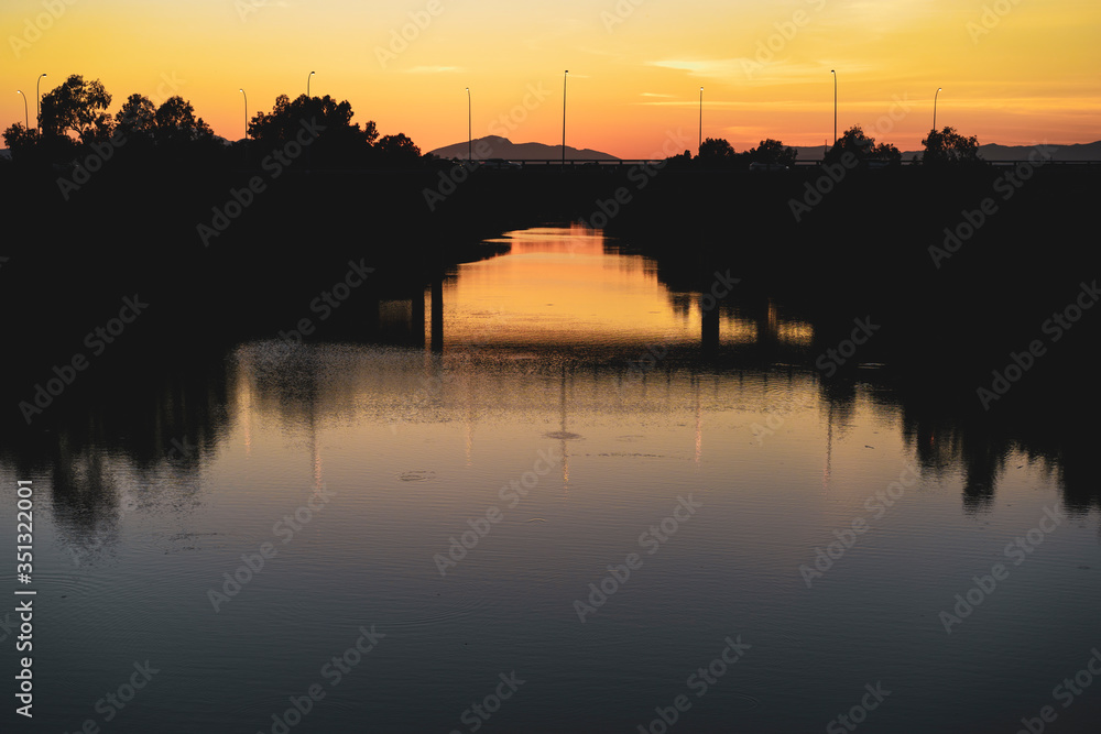 Silhouette of a bridge at sunset by a lake
