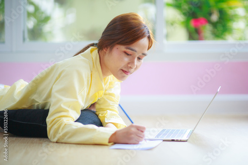 asian woman work at home with laptop laydown on floor with happiness and joyful