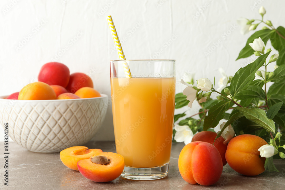 Composition with tasty apricots and juice on gray table Composition with tasty apricots and juice on gray table