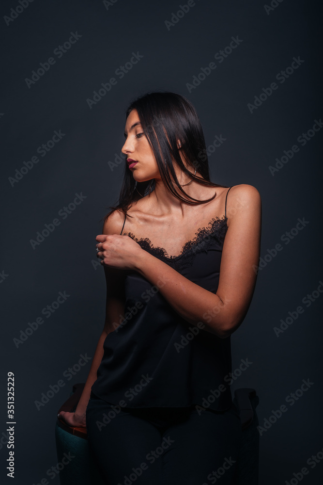 Beautiful sexy woman with straight black hair looking aside and being isolated on a dark background