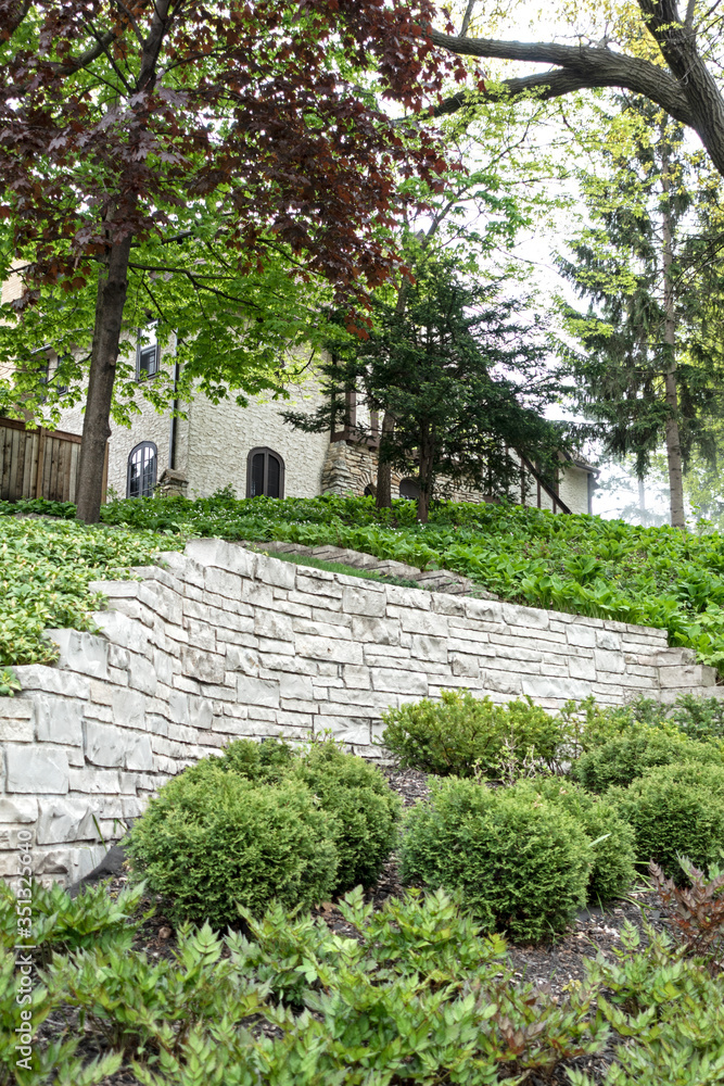 Flagstone wall at base of beautiful home with surrounding garden. St Paul Minnesota MN USA