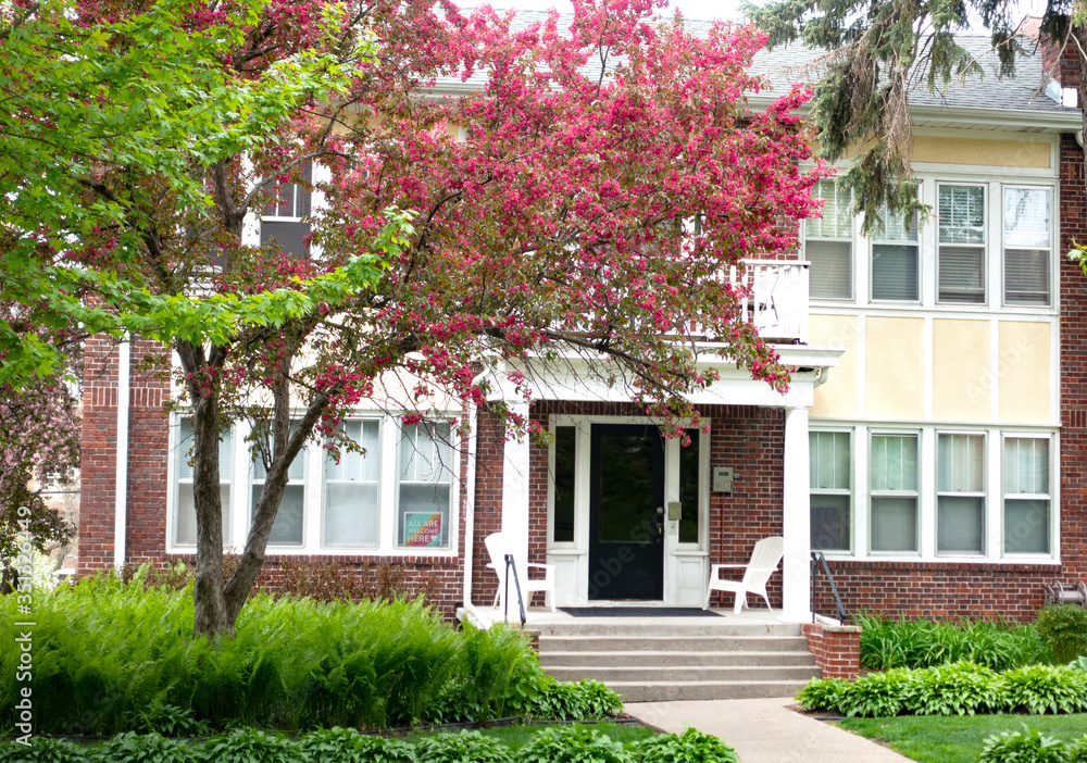 Attractive apartment building with a pink blooming fruit tree and gardens. St Paul Minnesota MN USA