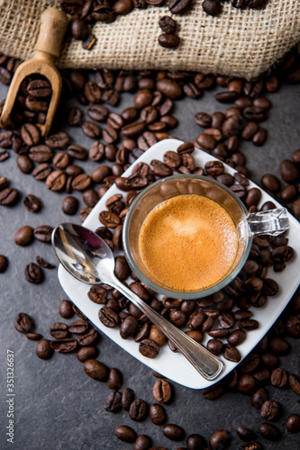 Italian espresso coffee in a glass cup on a black floor with coffee beans cutting light