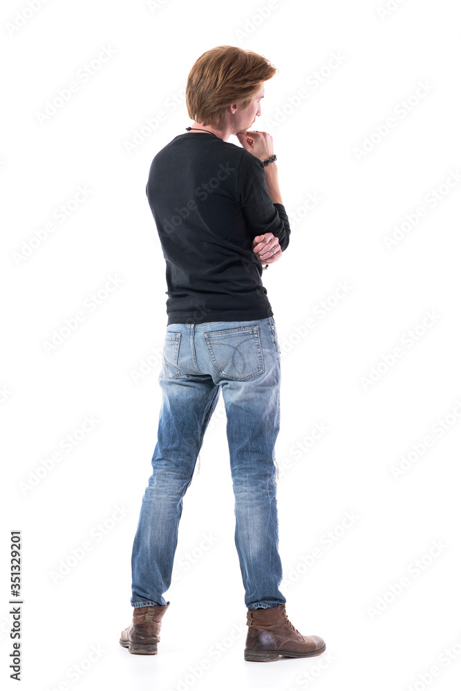 © sharplaninac - Back view of handsome young man watching interested at copy space with hand on chin. Full body length isolated on white background.