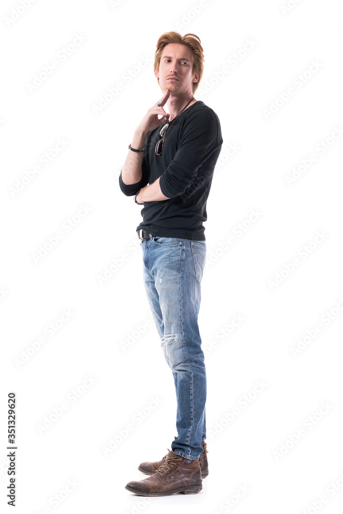 © sharplaninac - Displeased thoughtful young man waiting in line looking back with finger on chin. Full body length isolated on white background.