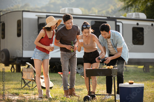 Happy young friends barbecuing outdoors