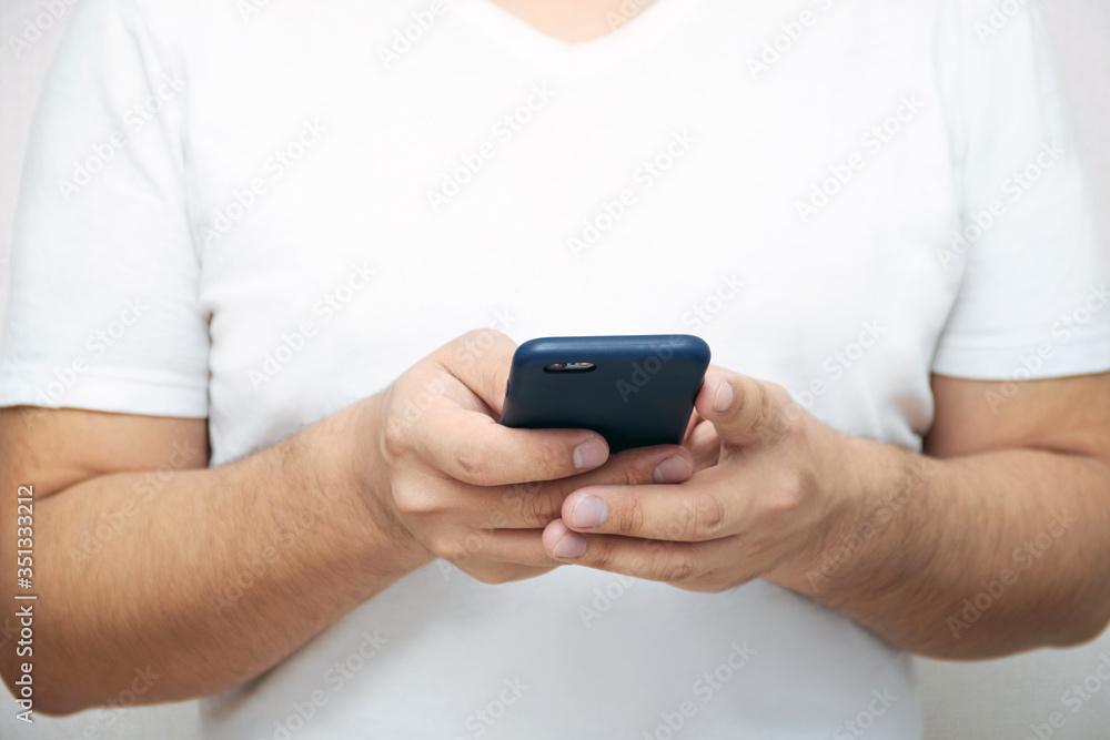 A person is holding a phone and tapping the screen on a white background with copy space. Concept of lifestyle business and Internet technologies in the office A person is holding a phone and tapping the screen on a white background with copy space. Concept of lifestyle business and Internet technologies in the office