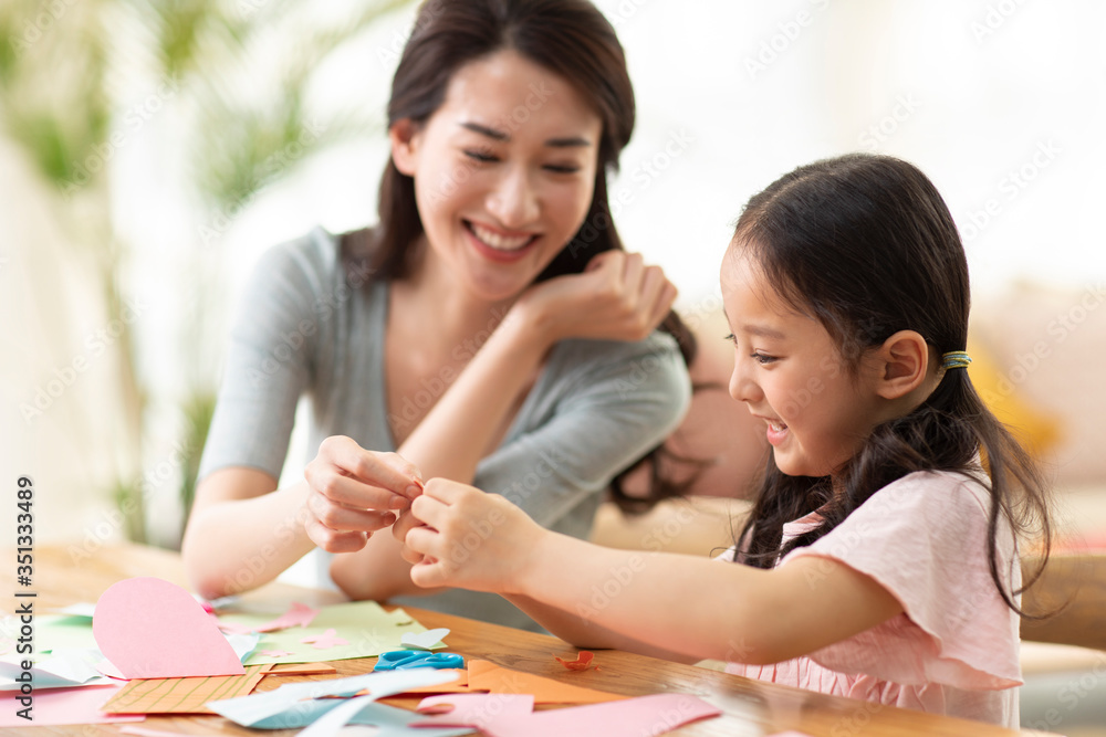 Happy mother and daughter cutting paper at home Happy mother and daughter cutting paper at home
