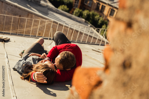 Loving couple husband and wife are lying on the roof of a beautiful city cuddling. Romantic date. Boyfriend girl on the roof of the house. Kiss on the roof.