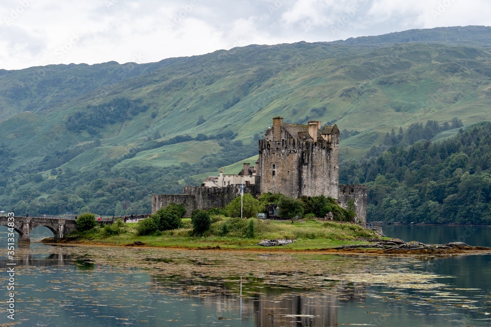 Eilean Donan Castle, Scotland in typical Scottish cloudy weather with a bridge and unrecognizable tourists