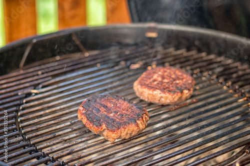 grilled meat - two burnt burgers on an outdoor grill