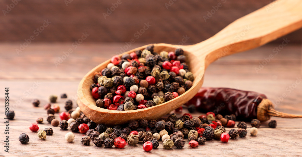 Mix peppercorns in spoon on wooden background Mix peppercorns in spoon on wooden background