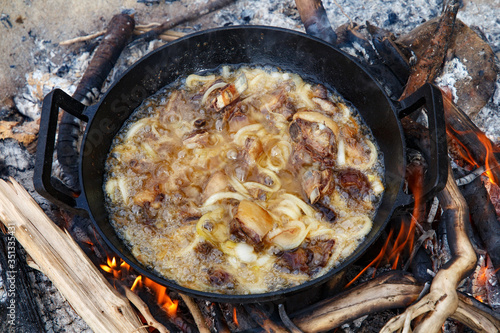 Pieces of lamb with onion are fried in boiling oil on the fire. As a stage in the preparation of traditional pilaf.