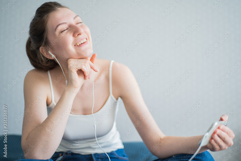 Watching movie on phone. The emotional reaction of a young woman from watching videos with headphones on her phone screen Watching movie on phone. The emotional reaction of a young woman from watching videos with headphones on her phone screen