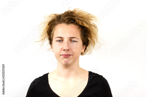 Close-up of a sad girl with disheveled hair looking slightly down. On white background. Emotion of sadness and disappointment.