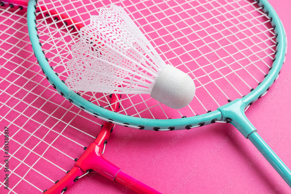 Badminton rackets and shuttlecock on a bright pink background. The concept of equipment for amateur sports. Minimalism.