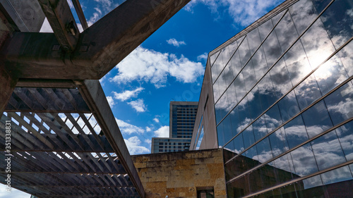 фотографія Looking up at a dramatic blue and white sky, framed by architectural steel lines and mirrored windows