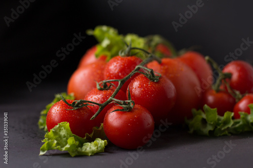 The fresh tomato with young herbs on a black background.