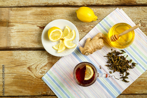 Cup of tea with lemon honey ginger and sprinkled tea on the table.