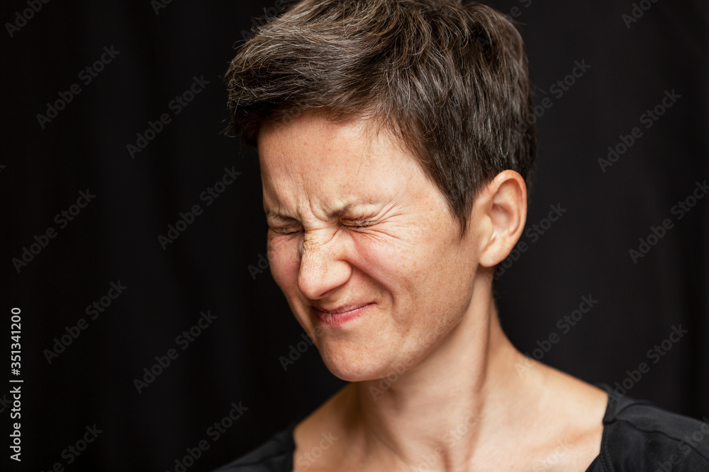 A woman with a short haircut and gray hair is emotionally angry by squinting her eyes. Anger and rage. Close-up. Black background. A woman with a short haircut and gray hair is emotionally angry by squinting her eyes. Anger and rage. Close-up. Black background.