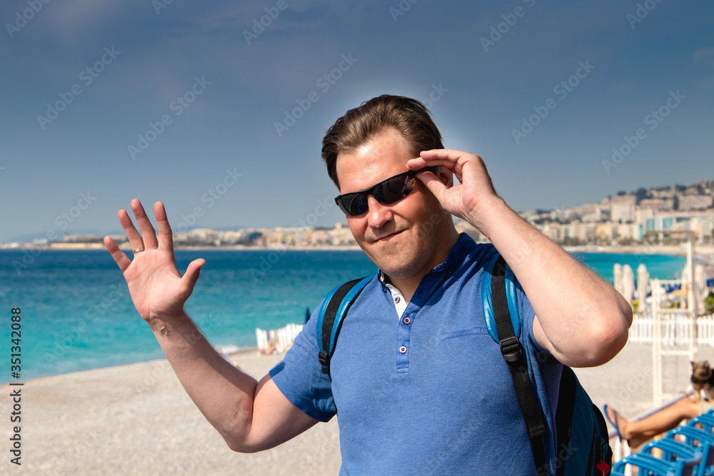 Saying hello. Young man waving to someone on the Promenade des Anglais. Nice. France.