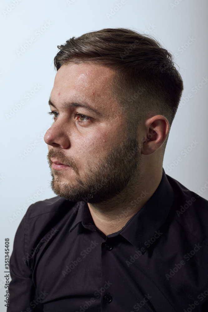 Fototapeta premium Young Bearded Dark Haired Man In Black Stylish Shirt, Jacket On Gray Background, Portrait Of A Confident, Serious Male, Purposeful Look To The Side