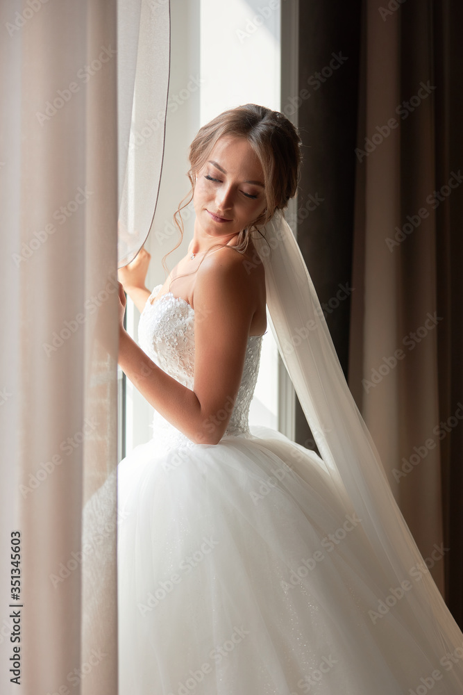 Nice girl in a wedding dress stands at the window Nice girl in a wedding dress stands at the window