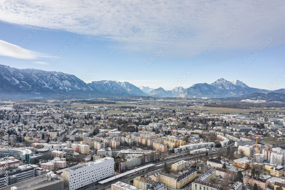 Aerial drone shot view of Salzburg aiglhof station with view of snowy alps mountain range in winter