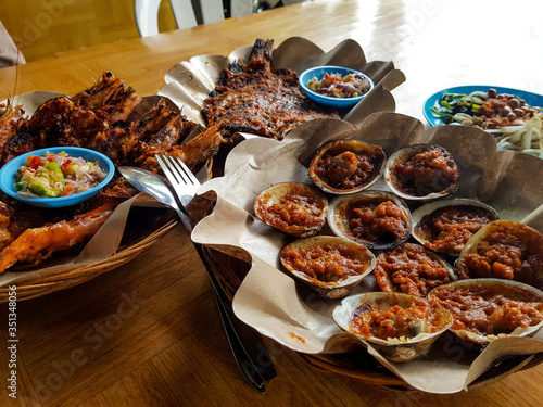 bali jimbaran seafood with chili matah or mattah sauce grilled big prawn, clams, fish and some traditional vegetable salad photo