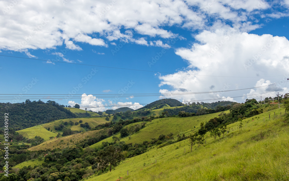 Montanhas verdes com céu azul e nuvens brancas em Camanducaia, MG, Brasil.