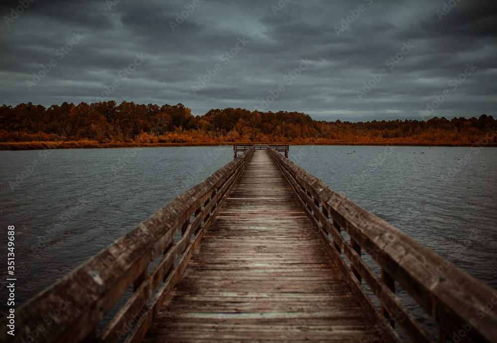 Wooden pier on a lake with a cloudy sky. 