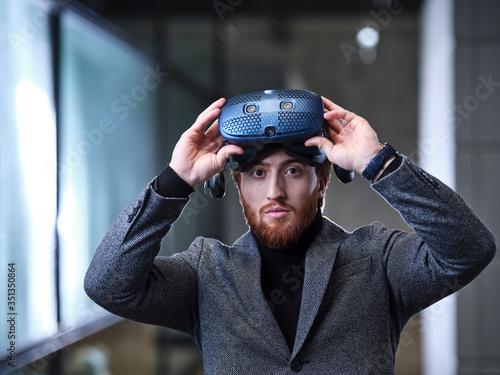 Portrait of businessman taking off VR glasses in modern office photo