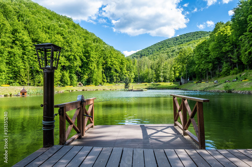 Wooden pier on the lake against the background of the forest and mountains.