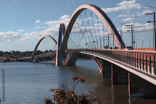 Fototapeta Naklejka Na Ścianę i Meble -  The monumental architecture of the JK bridge, a public place in Brasilia with three asymmetrical arches and geometric cross-shaped steel cables, forming a parabolic plane over the Paranoá lake