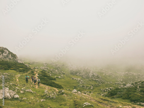 Spain, Cantabria, Group of backpackers hiking in Picos de Europa during foggy weather