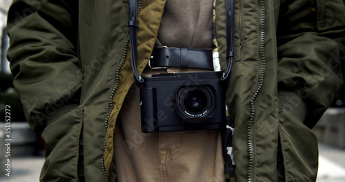 Digital camera with analog features hangs from the neck of a street photographer ready for another photo opportunity