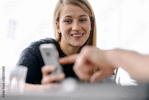 Portrait of smiling young woman and finger pointing on smartphone