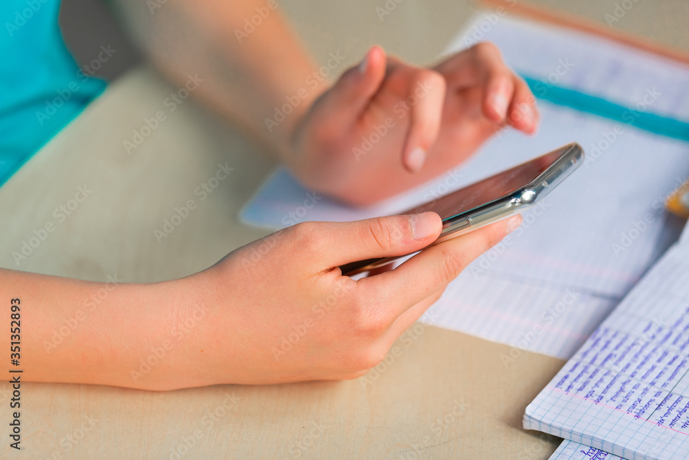 Fototapeta premium Beautiful young teenage school girl studying with smartphone, close up on hands with the mobile phone.