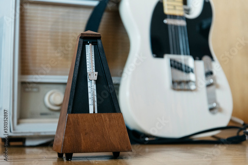 Metronome with electric guitar and old radio in the background