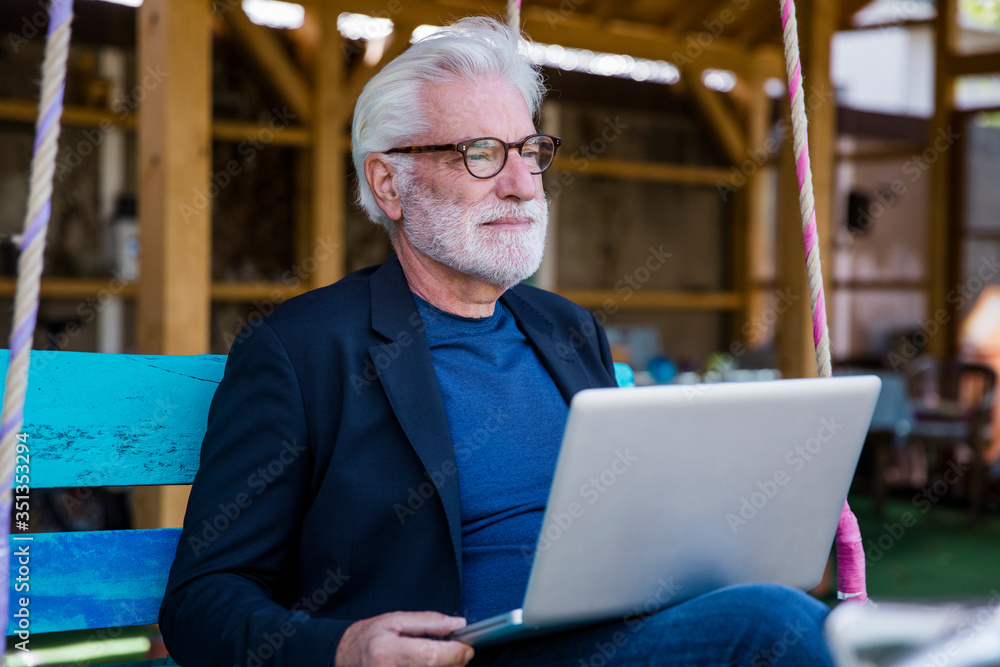 Portrait of senior man sitting outdoors with laptop Portrait of senior man sitting outdoors with laptop