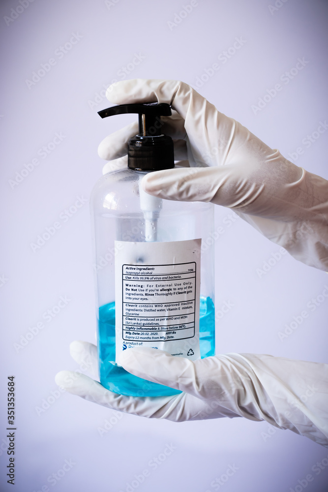 Presenting sanitizer bottle by both hands with medical latex gloves