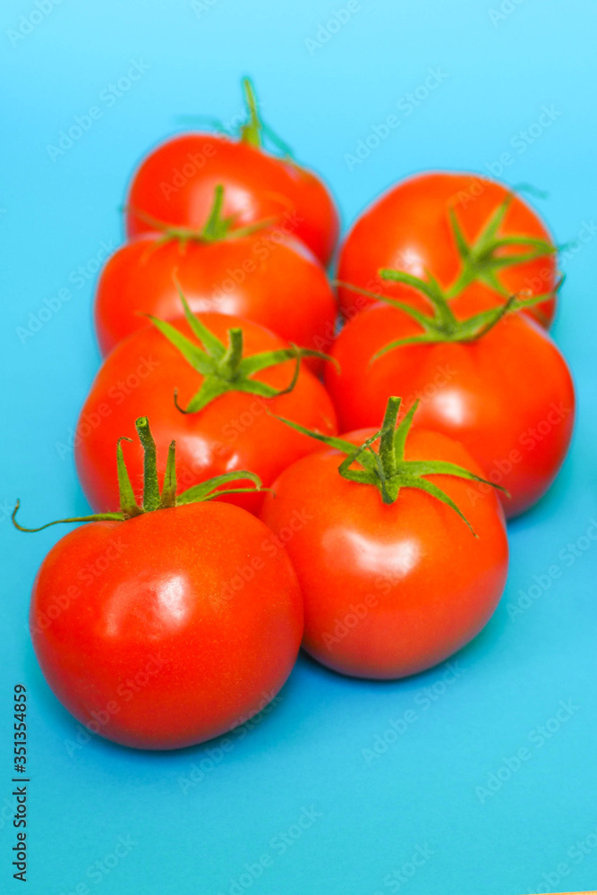 seven round ripe red tomatoes on a blue background. red raw vegetables seven round ripe red tomatoes on a blue background. red raw vegetables