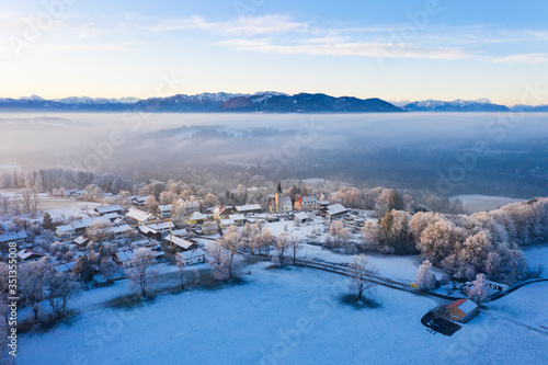 Germany, Bavaria, Hechenberg, Drone view of snow-covered countryside village at foggy dawn photo