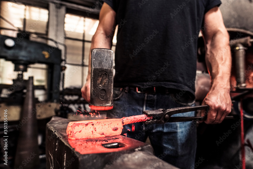 Knife maker working scattering borax over hot damask steel Knife maker working scattering borax over hot damask steel