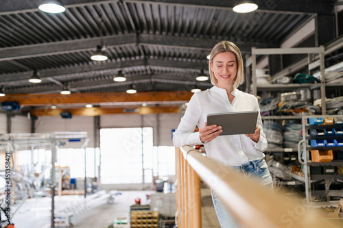 Smiling young woman using tablet in a factory