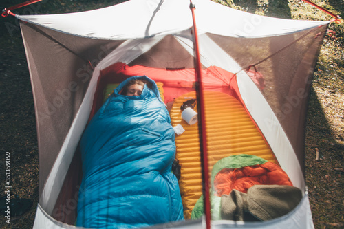 Young woman sleeping in sleeping bag in a tent photo