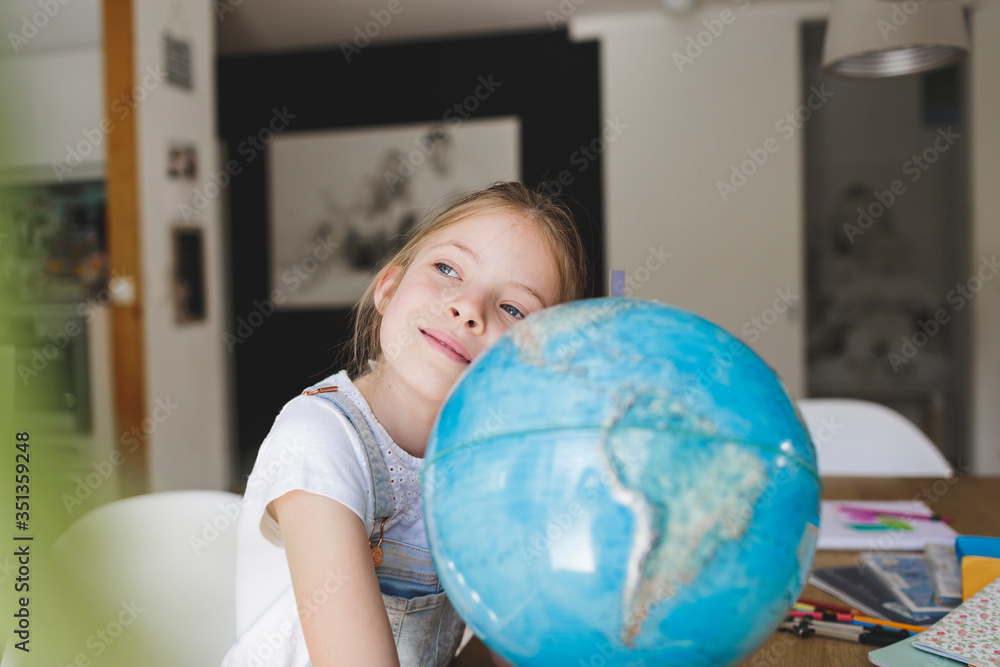 Portrait of daydreaming girl at home leaning on globe Portrait of daydreaming girl at home leaning on globe
