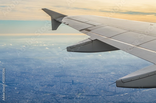 View over the clouds from the porthole of an airplane with plane wing over Paris at take off