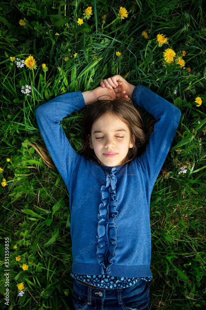 Portrait of girl with eyes closed relaxing on a meadow in spring